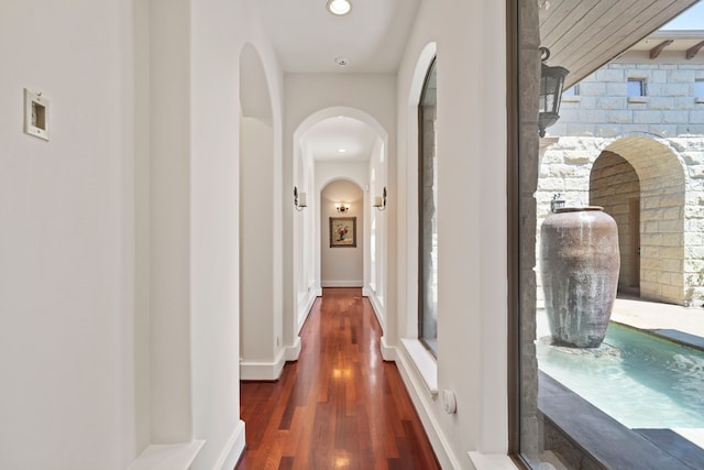hall featuring arched walkways and wood finished floors