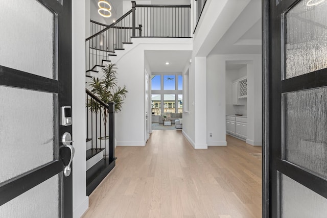 entrance foyer with a towering ceiling, wood finished floors, baseboards, and stairs