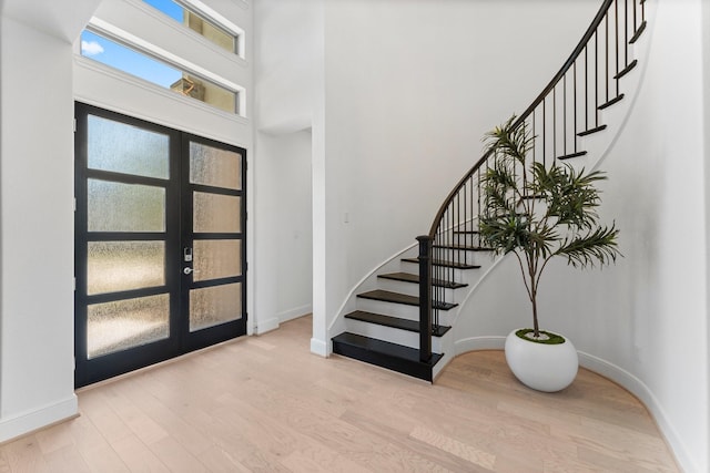 foyer with stairway, french doors, light wood-type flooring, and baseboards