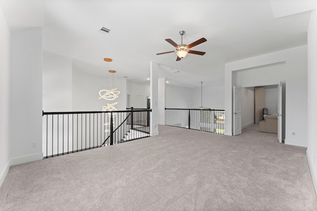 carpeted spare room with ceiling fan with notable chandelier, baseboards, and visible vents
