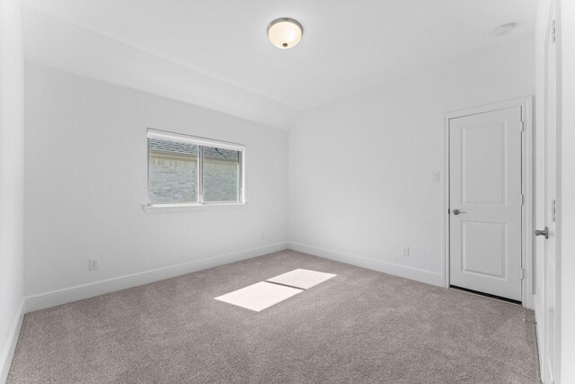 empty room featuring baseboards, carpet, and lofted ceiling