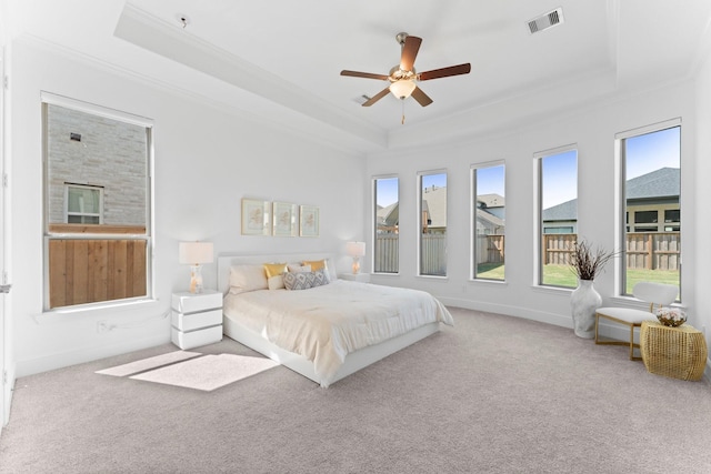 carpeted bedroom with visible vents, baseboards, a raised ceiling, ornamental molding, and ceiling fan