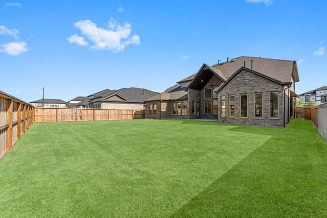 back of property with a yard, a fenced backyard, and brick siding