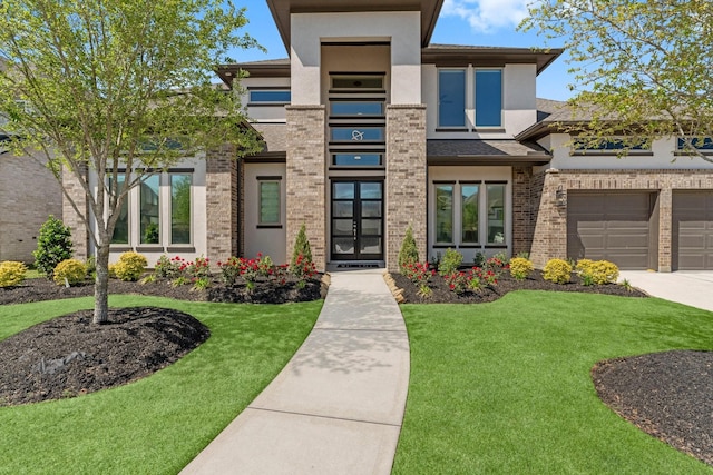 prairie-style home with concrete driveway, brick siding, stucco siding, and a front lawn