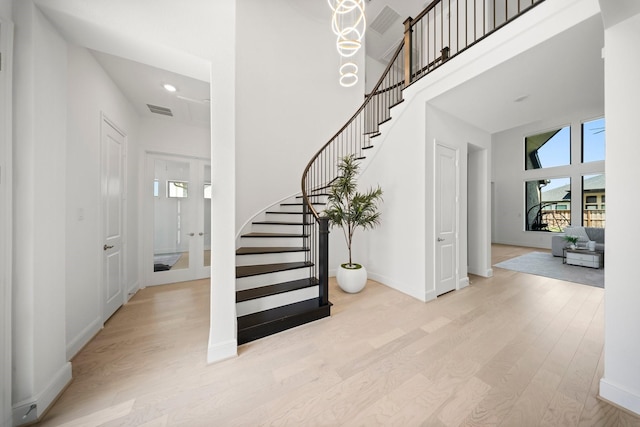 staircase featuring visible vents, a high ceiling, and wood finished floors