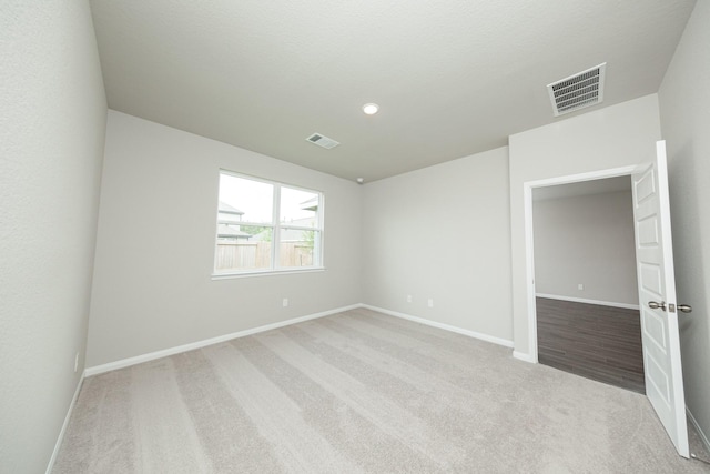 carpeted spare room with visible vents, baseboards, and recessed lighting