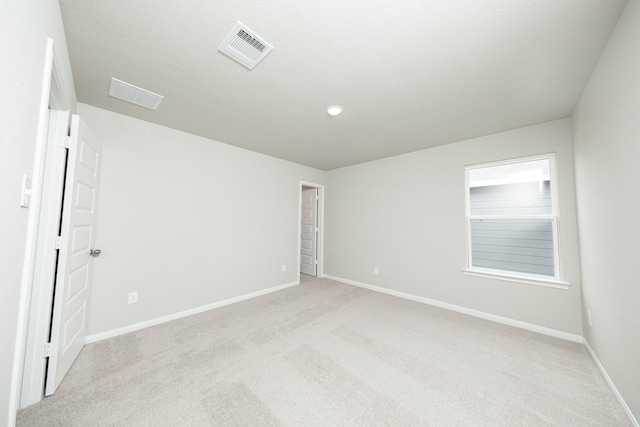 unfurnished room with baseboards, visible vents, and light colored carpet