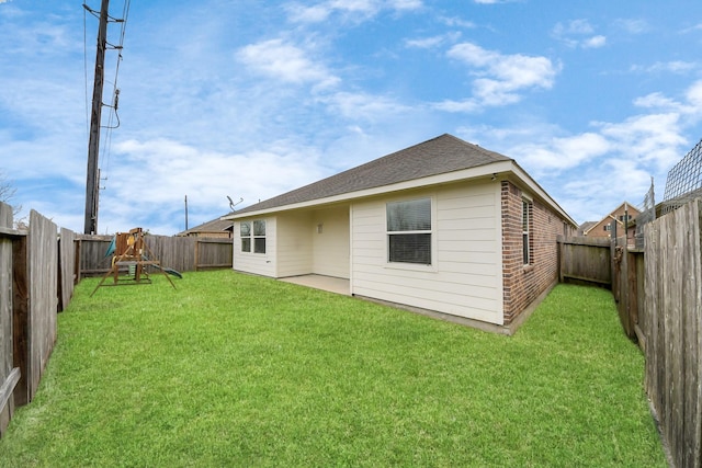 rear view of house with brick siding, roof with shingles, a fenced backyard, and a lawn