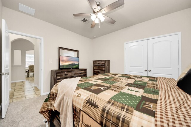bedroom with light tile patterned floors, visible vents, a closet, baseboards, and arched walkways
