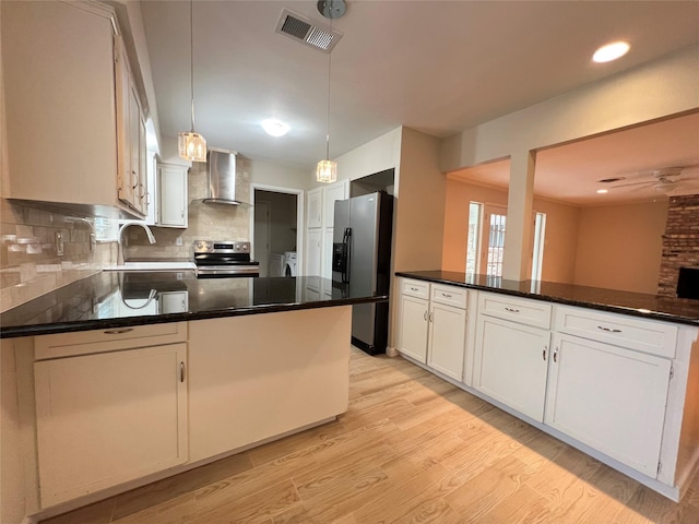 kitchen featuring visible vents, wall chimney range hood, refrigerator with ice dispenser, light wood-style flooring, and electric range