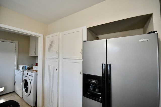 laundry area featuring light tile patterned floors, washing machine and clothes dryer, and cabinet space