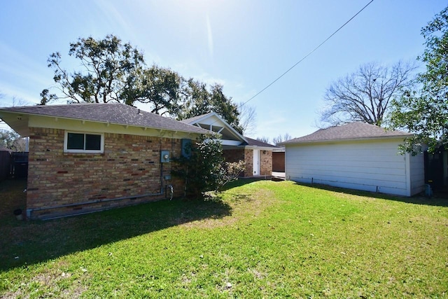 rear view of house featuring a yard and brick siding