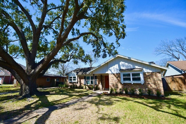 single story home featuring a front yard, brick siding, and fence