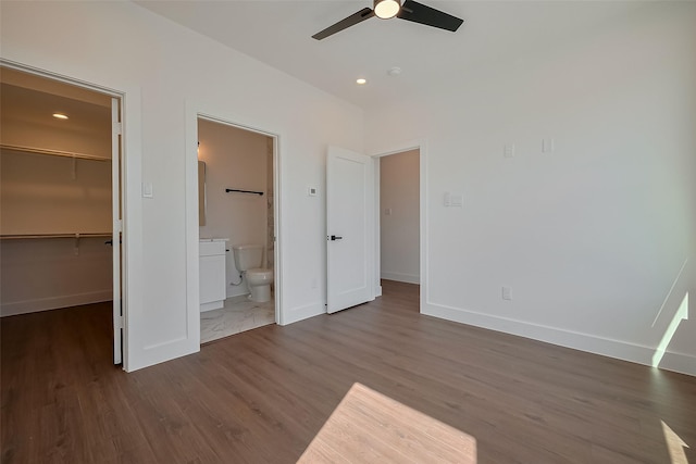 unfurnished bedroom featuring recessed lighting, wood finished floors, a spacious closet, and baseboards