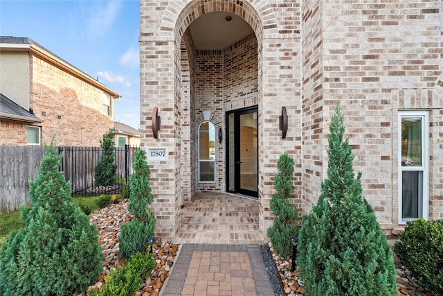doorway to property with fence and brick siding