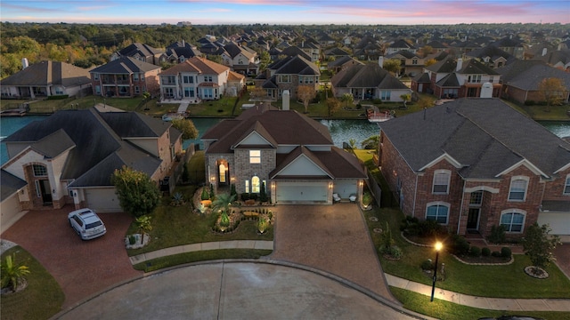 aerial view at dusk featuring a residential view and a water view