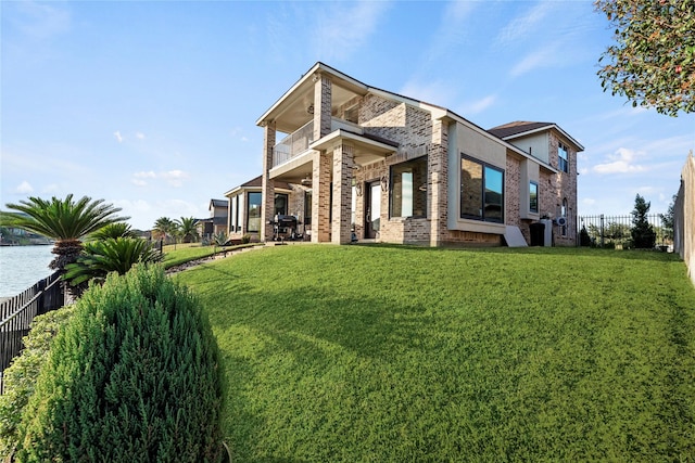 exterior space with brick siding, a lawn, a fenced backyard, and a balcony