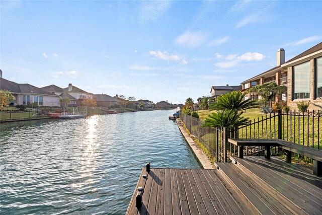 dock area featuring a yard, fence, a residential view, and a water view