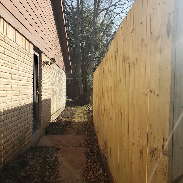 view of side of home with brick siding and fence