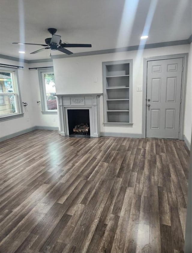 unfurnished living room with built in features, wood finished floors, baseboards, and a ceiling fan