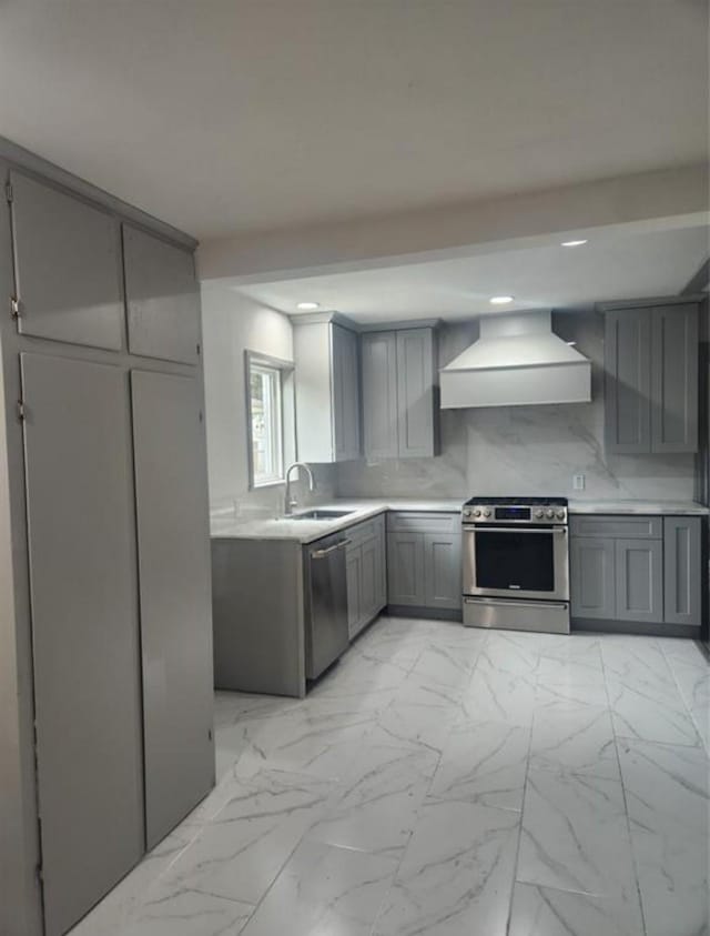 kitchen featuring stainless steel appliances, premium range hood, a sink, and gray cabinets