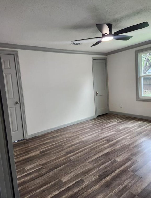 empty room with ornamental molding, dark wood-style floors, a textured ceiling, visible vents, and ceiling fan