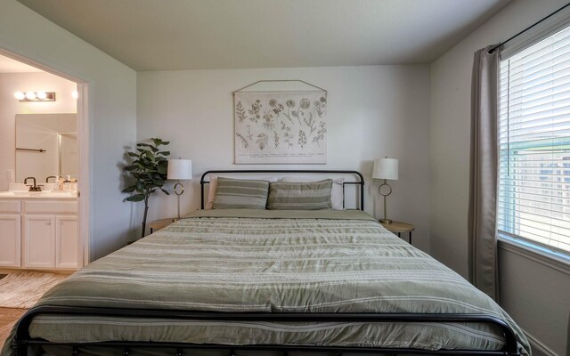 bedroom featuring a sink, multiple windows, connected bathroom, and wood finished floors