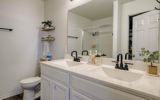 full bathroom with a sink, toilet, double vanity, and a stall shower