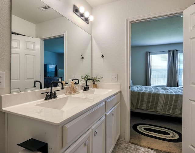 ensuite bathroom with double vanity, a sink, visible vents, and ensuite bath