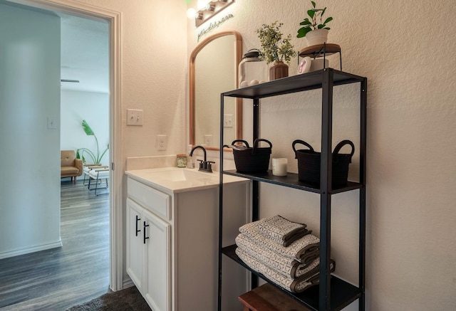 bathroom with a textured wall, vanity, and wood finished floors