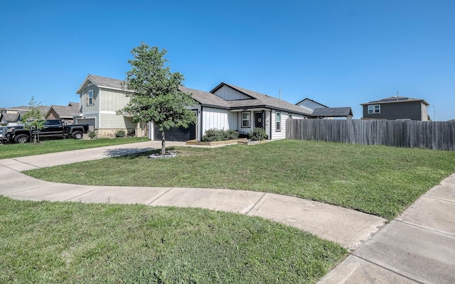 view of front of house with concrete driveway, a front yard, fence, and a garage