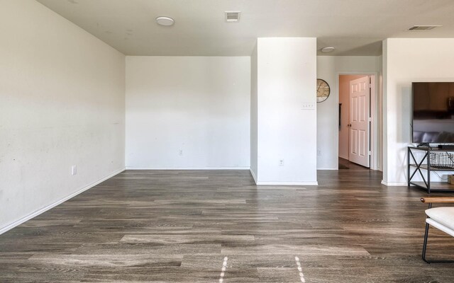 unfurnished living room featuring visible vents, baseboards, and wood finished floors