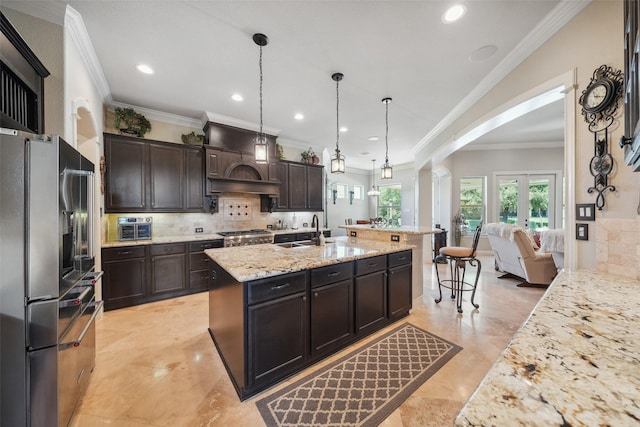 5924 Oak Leaf Ct, Conroe, TX 77304 - kitchen with stainless steel fridge, arched walkways, tasteful backsplash, a kitchen island with sink, and dark brown cabinetry