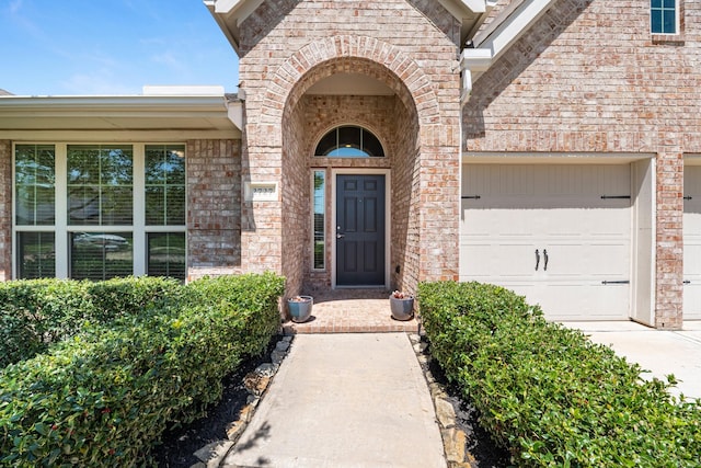 property entrance with an attached garage, concrete driveway, and brick siding