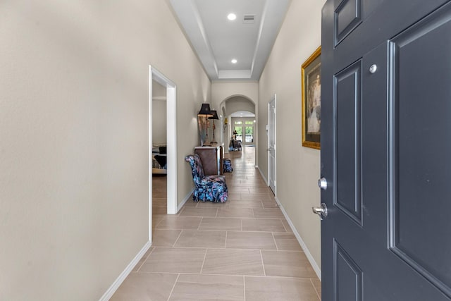 hall featuring light tile patterned floors, arched walkways, visible vents, recessed lighting, and baseboards