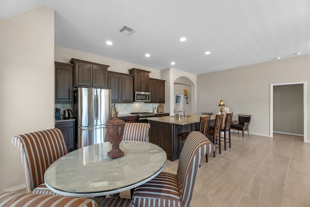 dining space with visible vents, baseboards, recessed lighting, and arched walkways