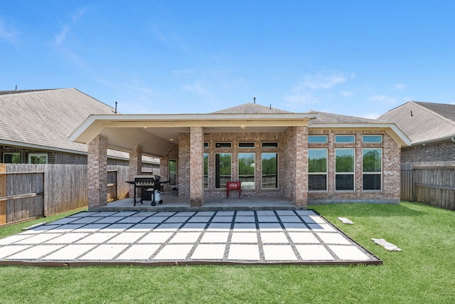 rear view of property featuring a patio, brick siding, a fenced backyard, and a lawn