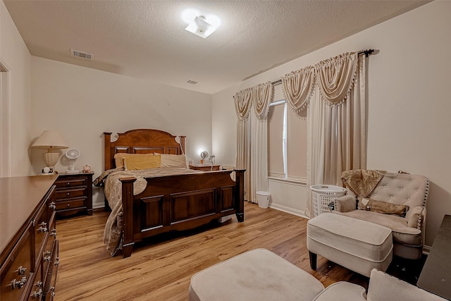 bedroom featuring visible vents, light wood-style floors, and a textured ceiling