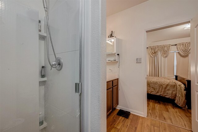 bathroom featuring baseboards, a stall shower, wood finished floors, and vanity