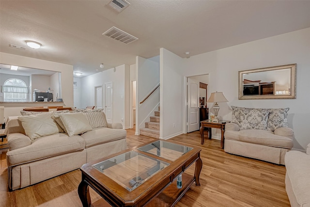 living area with light wood finished floors, visible vents, and stairs