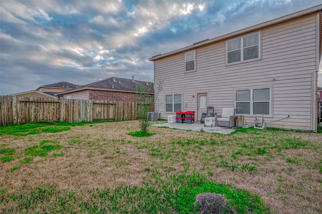 back of house featuring a fenced backyard, a patio, and a lawn