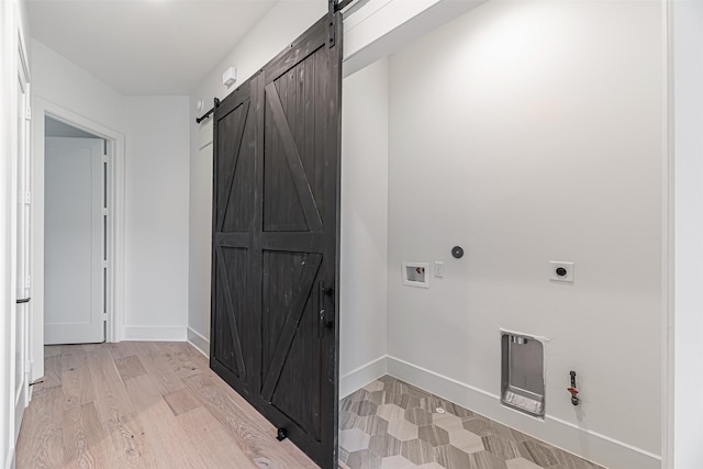 laundry area with hookup for an electric dryer, gas dryer hookup, a barn door, laundry area, and hookup for a washing machine