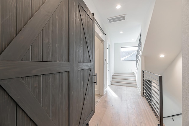 829 Alexander St, Houston, TX 77007 - hallway featuring a barn door, light wood-style floors, and recessed lighting
