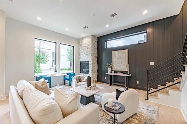 living room featuring light wood-type flooring, visible vents, and stairway