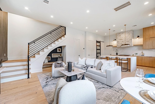 living area with visible vents, light wood-style flooring, stairway, and recessed lighting
