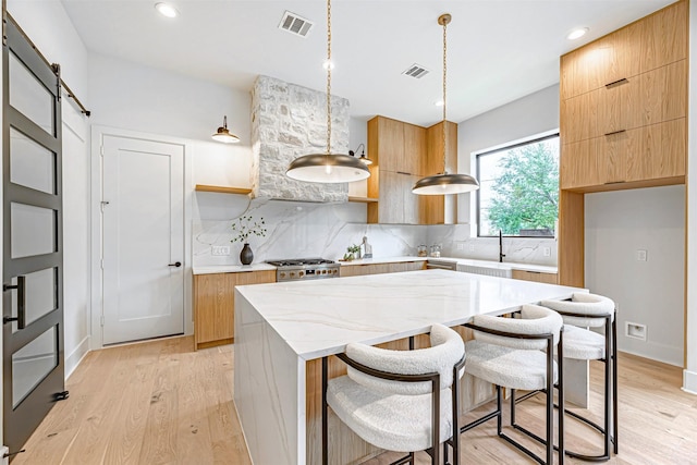 kitchen featuring modern cabinets, light wood-type flooring, visible vents, a barn door, and a center island