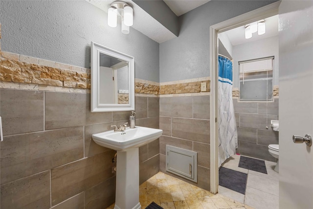 13918 Bretagne Dr, Houston, TX 77015 - bathroom featuring a wainscoted wall, a shower with curtain, toilet, tile walls, and tile patterned flooring