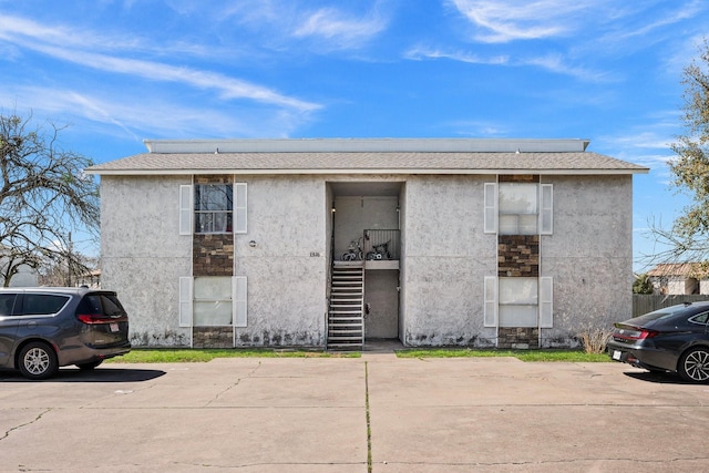 view of property with uncovered parking and stairway
