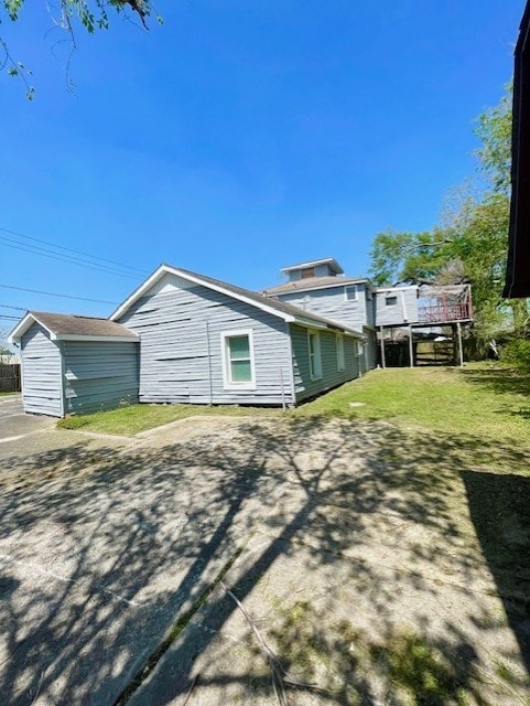 back of house with a shed, an outdoor structure, and a lawn