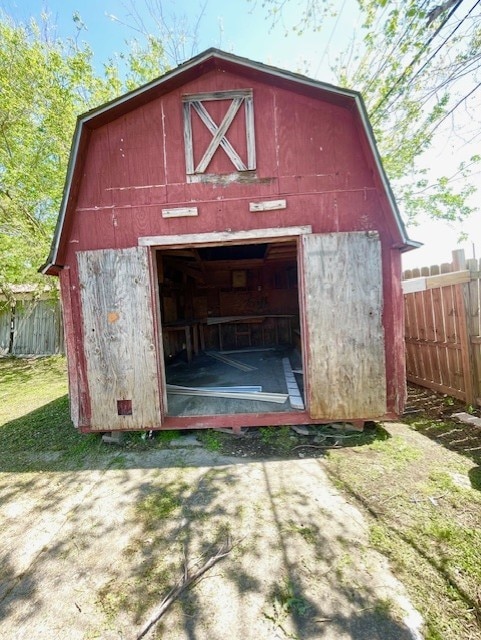 view of barn featuring driveway and fence